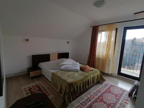 een slaapkamer met een bed en een groot raam bij Garofita Pietrei Craiului in Peştera