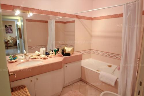 une salle de bain avec un lavabo, une baignoire et un miroir dans l'établissement Alessandra, à Cannes