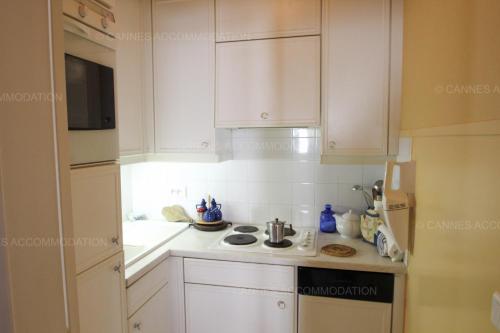 une cuisine avec des armoires blanches et un four à plaques de cuisson dans l'établissement Alessandra, à Cannes