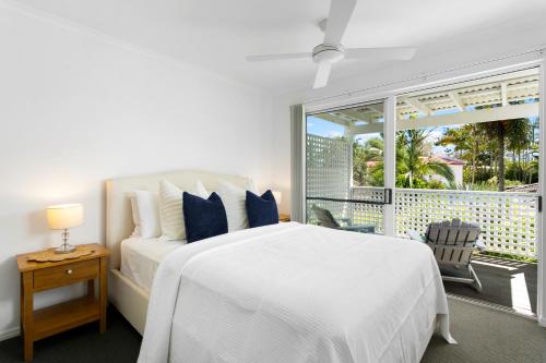 a white bedroom with a bed and a large window at Noosa Sunseeker-walk to cafes & river, pet friendly in Noosaville