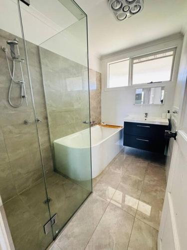 a bathroom with a shower and a tub and a sink at House in Sunshine close to city in Sunshine