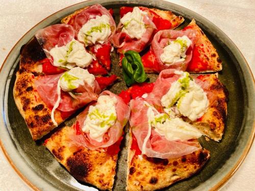 a plate with a pizza with meat and tomatoes at Hotel Rovereto in Rovereto
