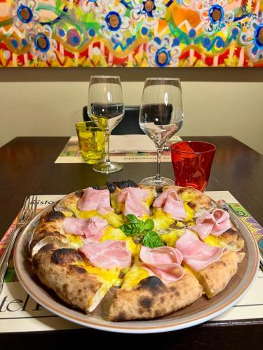 a pizza on a plate on a table with two wine glasses at Hotel Rovereto in Rovereto