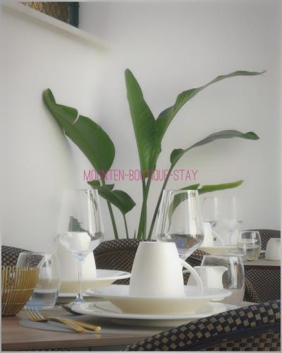 a table with plates and glasses and a potted plant at MOONTEN Boutique Stay in Sóller