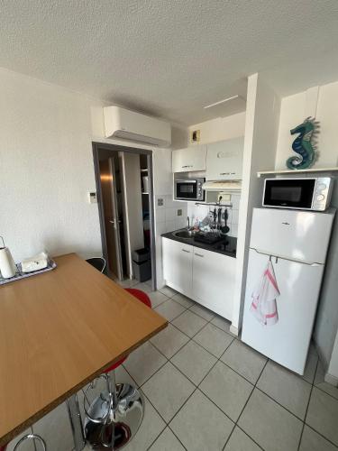 - une cuisine avec des appareils blancs et une table en bois dans l'établissement La mer pour décor de fond, à Saint Pierre La Mer