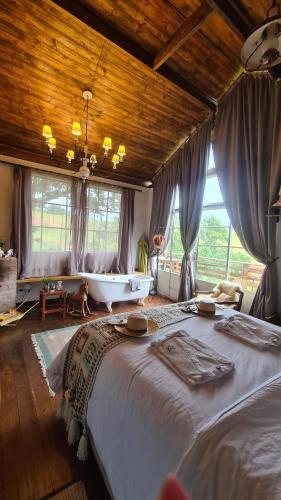 a bedroom with a large bed and a bath tub at Chalé Vilarejo - Vila Monte Cunha in Cunha