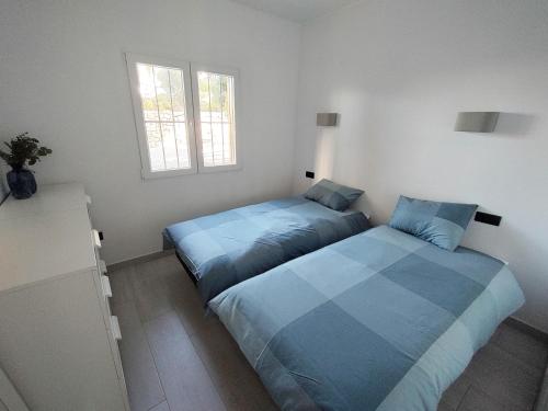 twee bedden in een kamer met twee ramen bij Casita Leo in Teulada