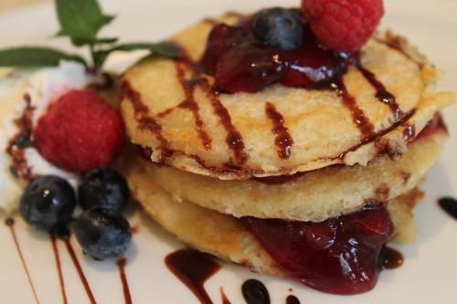 a stack of pancakes with fruit on a plate at Hotel Vitalia in Boszkowo