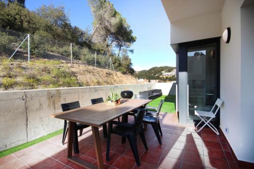 Une table et des chaises en bois sont disponibles sur la terrasse. dans l'établissement Ático con terraza y vistas a la montaña en Arenys by Alterhome, à Arenys de Munt