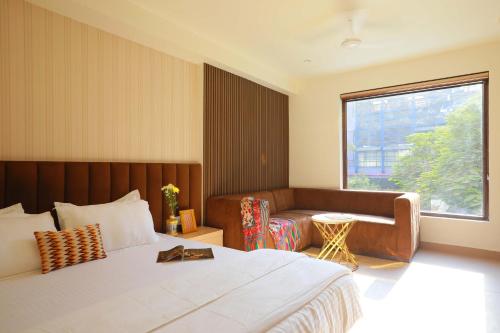 a bedroom with a bed and a couch and a window at Hotel Adora in New Delhi