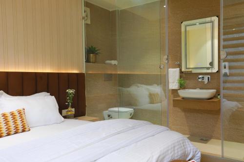a bedroom with a bed and a bathroom with a sink at Hotel Adora in New Delhi