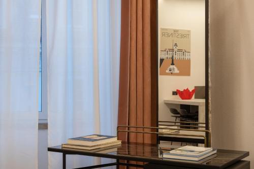 a table with books on it in front of a mirror at San Nicolò Suites in Trieste