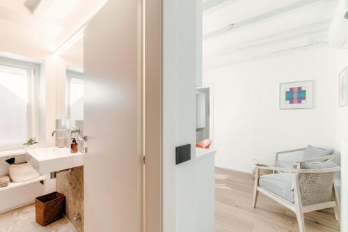 a white bathroom with a sink and a chair at La casa di Piera in Como