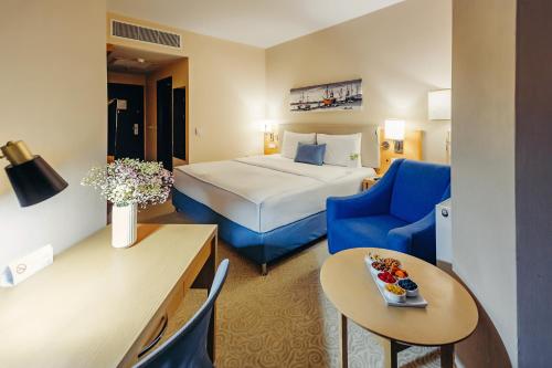 Pokój hotelowy z łóżkiem i niebieskim krzesłem w obiekcie Dedeman Oskemen Tavros Hotel w mieście Ust-Kamienogorsk