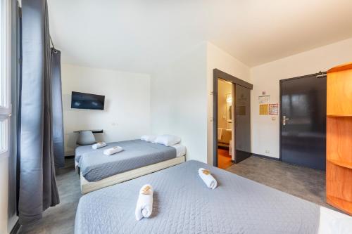 two beds in a hotel room with towels on them at Hôtel La Nonette ASTERIX, CDG AIRPORT & PARIS CENTRE in Orry-la-Ville