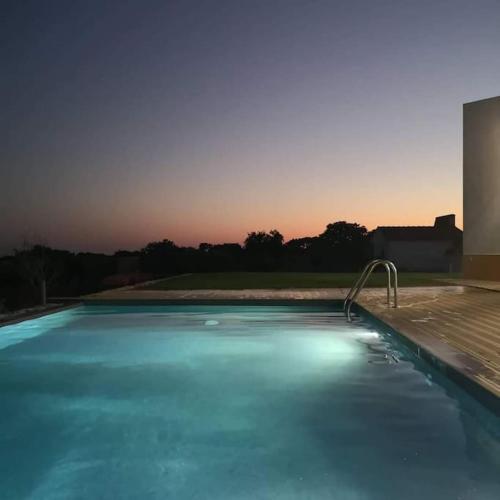 a swimming pool with blue water in front of a building at Turismo Rural Pedremoura in Vila Ruiva
