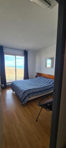 une chambre avec un lit et une grande fenêtre dans l'établissement La mer pour décor de fond, à Saint Pierre La Mer