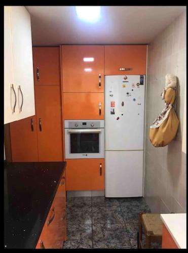 eine Küche mit Holzschränken und einem weißen Kühlschrank in der Unterkunft Mar y Gibraltar: ¡Tu Refugio! in La Línea de la Concepción