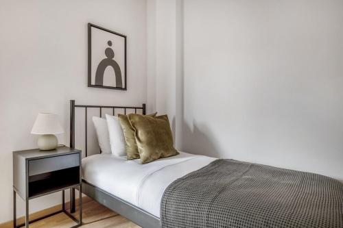 een witte slaapkamer met een bed en een nachtkastje bij Blueground Les Corts balcony nr Camp Nou BCN-82 in Barcelona