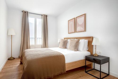 a white bedroom with a bed and a window at Blueground Dreta de lEixample nr pl catalunya BCN-48 in Barcelona