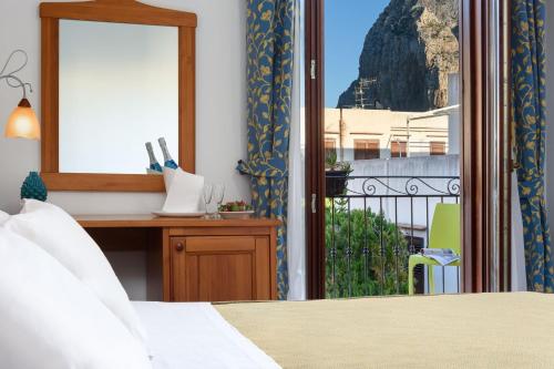 Schlafzimmer mit einem Bett, einem Schreibtisch und einem Fenster in der Unterkunft La Meridiana Hotel in San Vito lo Capo