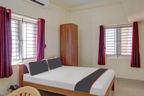 um quarto com uma cama grande e cortinas vermelhas em Hotel Orchid Residency Medavakkam em Chennai