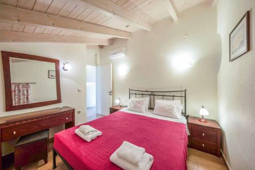 Almiros BeachにあるVilla Pitteriのベッドルーム(大型赤いベッド1台、鏡付)