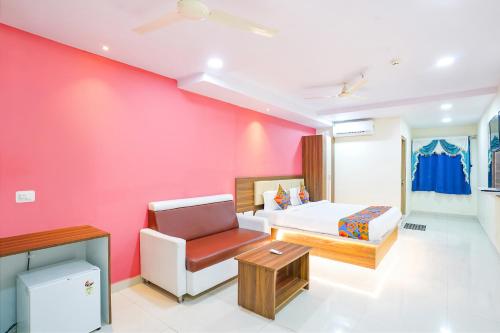 ein Schlafzimmer mit einer rosa Wand mit einem Bett und einem Stuhl in der Unterkunft FabHotel Prime SYN Grand in Hyderabad