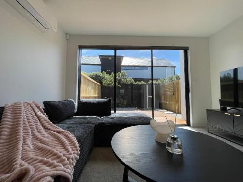 a living room with a couch and a table at Luxury 2 Bedroom Townhouse Opposite Merivale Mall in Christchurch