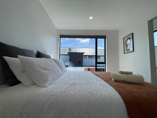 a bedroom with a large bed with a large window at Luxury 2 Bedroom Townhouse Opposite Merivale Mall in Christchurch