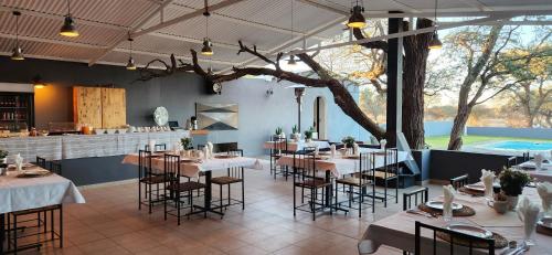 um restaurante com mesas e cadeiras e uma árvore em Jansen Kalahari Guest Farm em Hoachanas