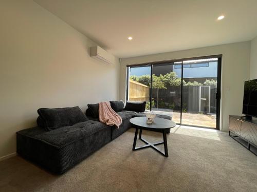 a living room with a couch and a table at Luxury 2 Bedroom Townhouse Opposite Merivale Mall in Christchurch
