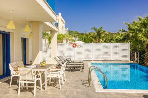 a patio with a table and chairs next to a pool at Villa Seashell Skala in Spathíon