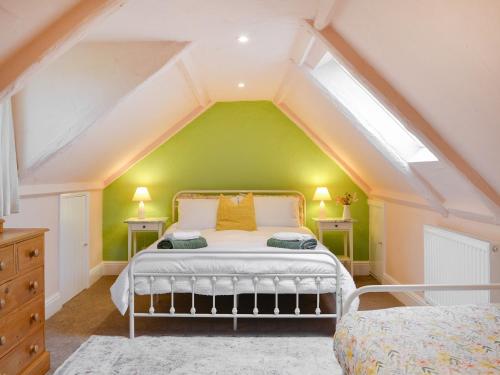 a bedroom with a bed with a green wall at Cartwheel Cottage in Hayton