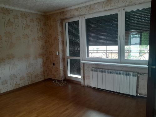 une pièce vide avec deux fenêtres et un radiateur dans l'établissement pokoje na wynajem, à Tuchola