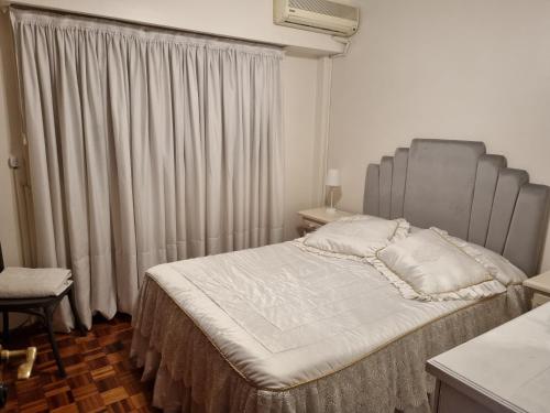 Elegante 3 dormitorios في بوينس آيرس: غرفة نوم مع سرير مع اللوح الأمامي الرمادي والستائر