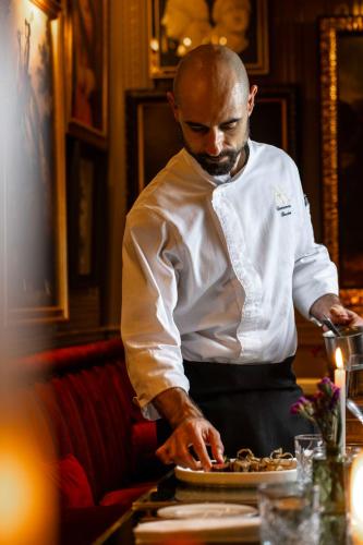 a man preparing a plate of food on a table at Maalot Roma - Small Luxury Hotels of the World in Rome