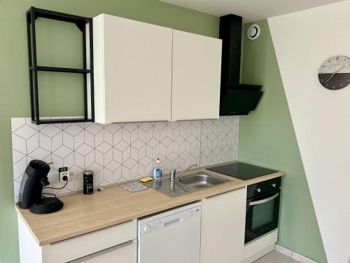 une petite cuisine avec des armoires blanches et un évier dans l'établissement Havre de tranquillité à 13Kms des plages de Royan, à Le Gua