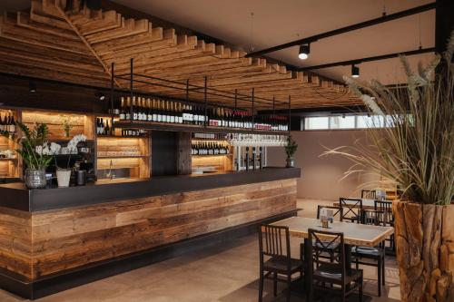 un ristorante con bar in legno con tavoli e sedie di Hotel Leonard a Nova Ponente