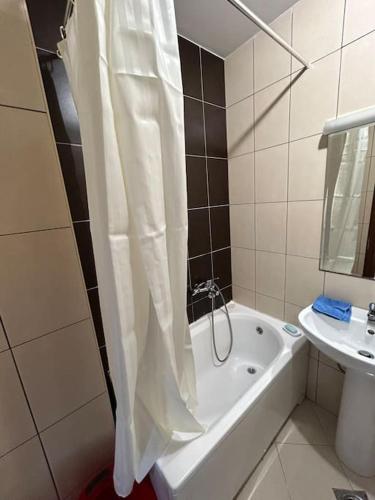 ポドゴリツァにあるStylish_apartmentのバスルーム(シャワーカーテン、バスタブ、シンク付)