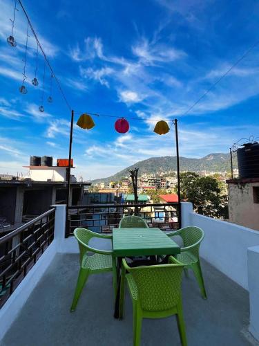 a green table and chairs on a balcony with umbrellas at Gangesh Hotel in Rishīkesh