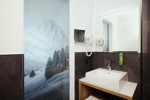 a bathroom with a sink and a mirror at Hotel Leonard in Nova Ponente