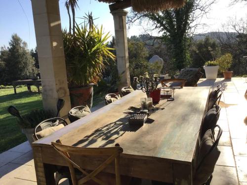 une table en bois entourée de chaises sur la terrasse. dans l'établissement Magnifique Mas provençal dans le Luberon avec vue, à Pierrevert
