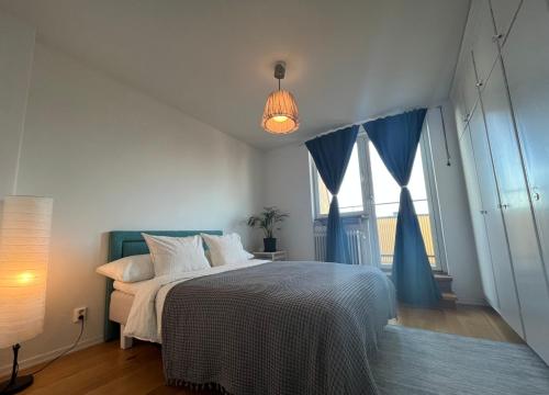 a bedroom with a large bed with blue curtains at Sky view apartment, Stockholm in Solna