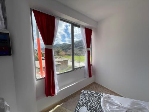 a bedroom with a window with red curtains and a bed at Hotel Bar Restaurant Mete in Peshkëpi