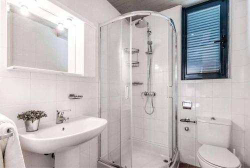 a white bathroom with a shower and a sink at Villa Zante in Barbati