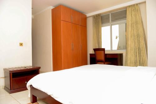 a bedroom with a bed and a cabinet and a desk at Nobilis Senior Suite a very good choice for a great vacational experience in Kigali