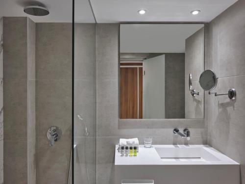 a bathroom with a sink and a shower with a mirror at Atlantica Sungarden Park in Ayia Napa