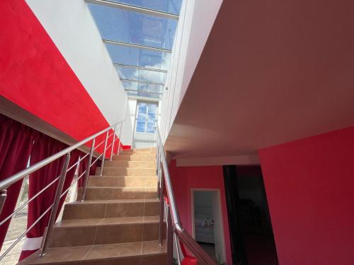 a stairway in a building with a red wall and a window at Hotel Bar Restaurant Mete in Peshkëpi