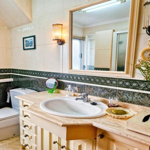 W łazience znajduje się umywalka, lustro i toaleta. w obiekcie Beachfront Nautical Apartment w mieście Benimagrell